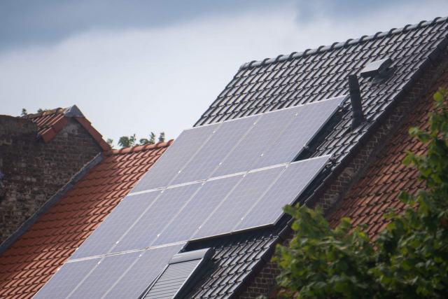 Panneaux photovoltaïques sous la neige devant une éolienne