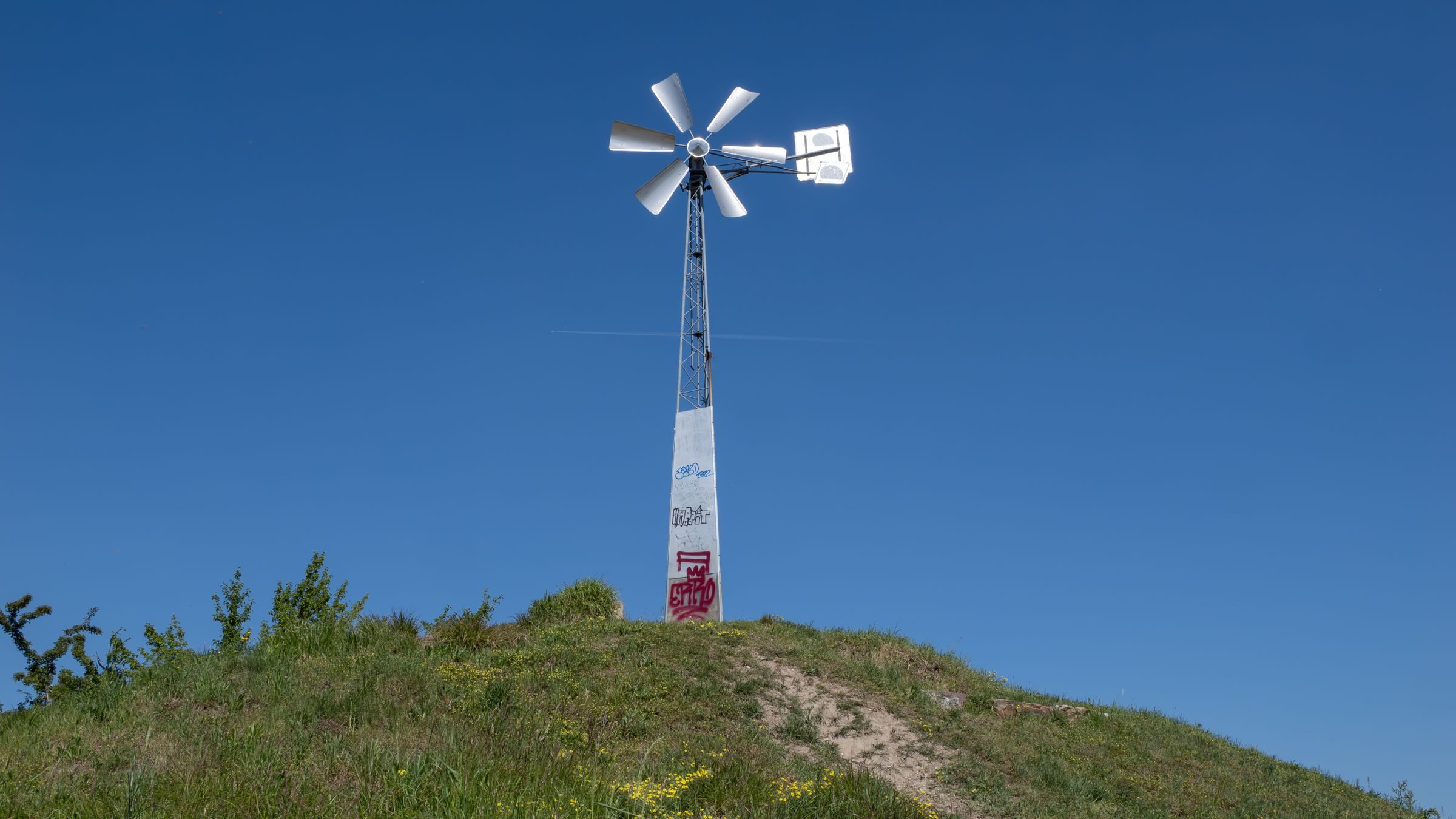 Éolienne à axe vertical sur un toit à côté d'une éolienne tripale