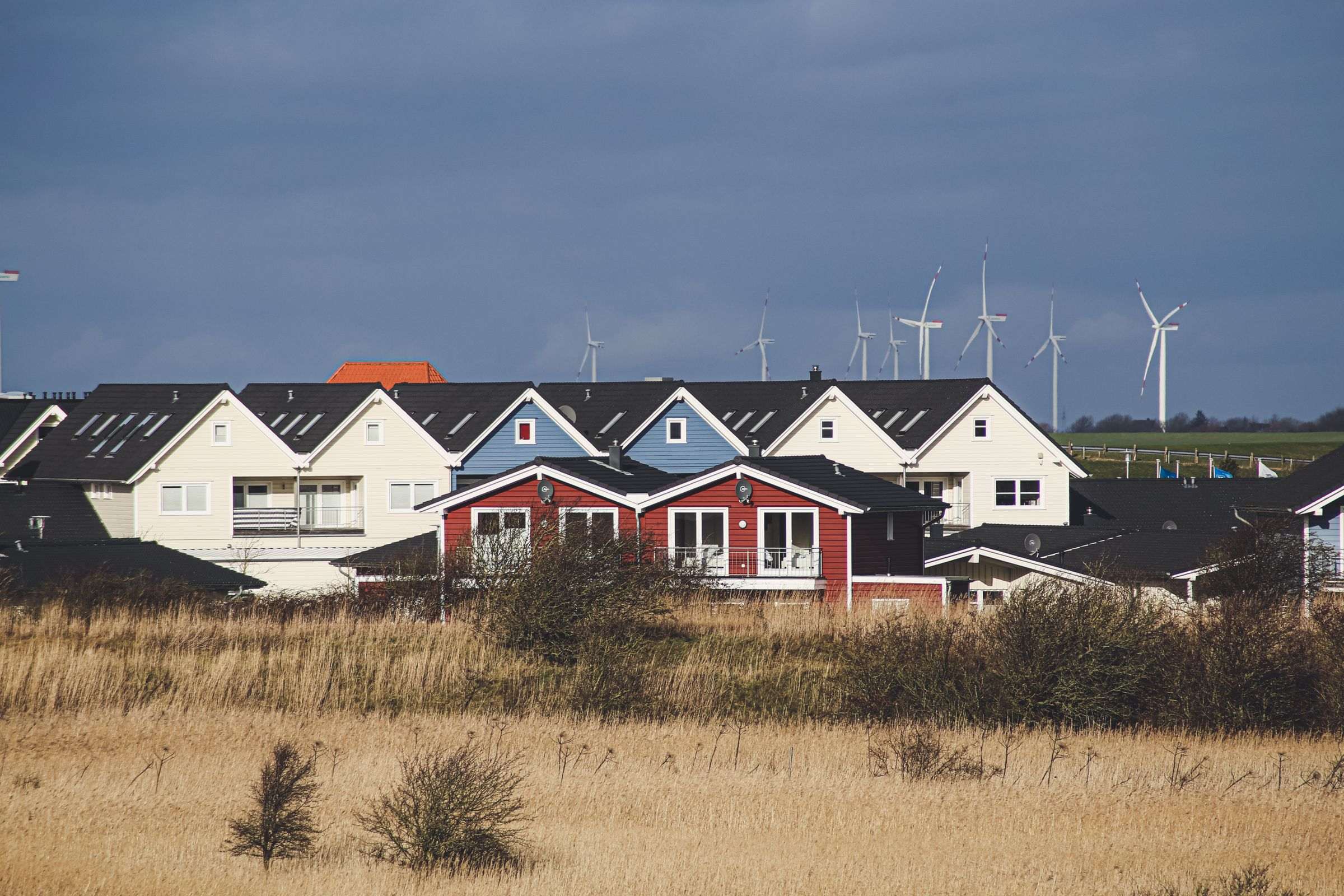 Maisons d’un village et éoliennes à l’horizon